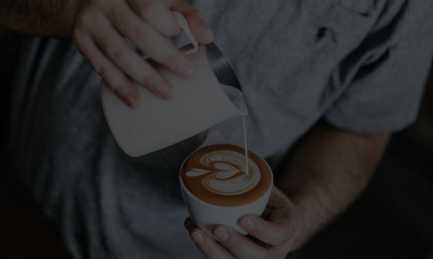 Hot water being poured into a cup of coffee from a kettle.